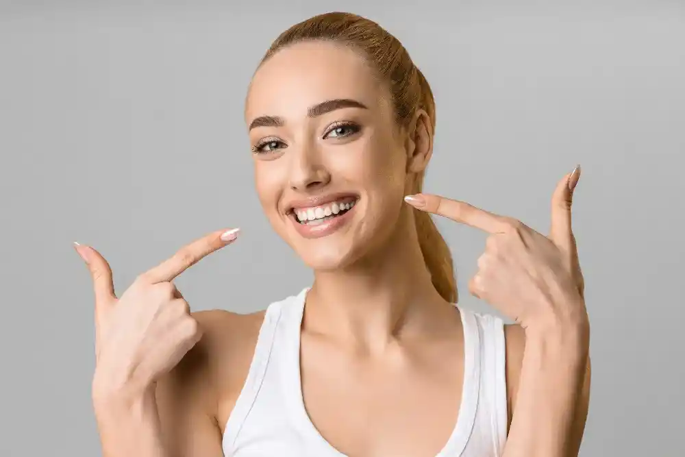 Patient smiling and pointing at her teeth
